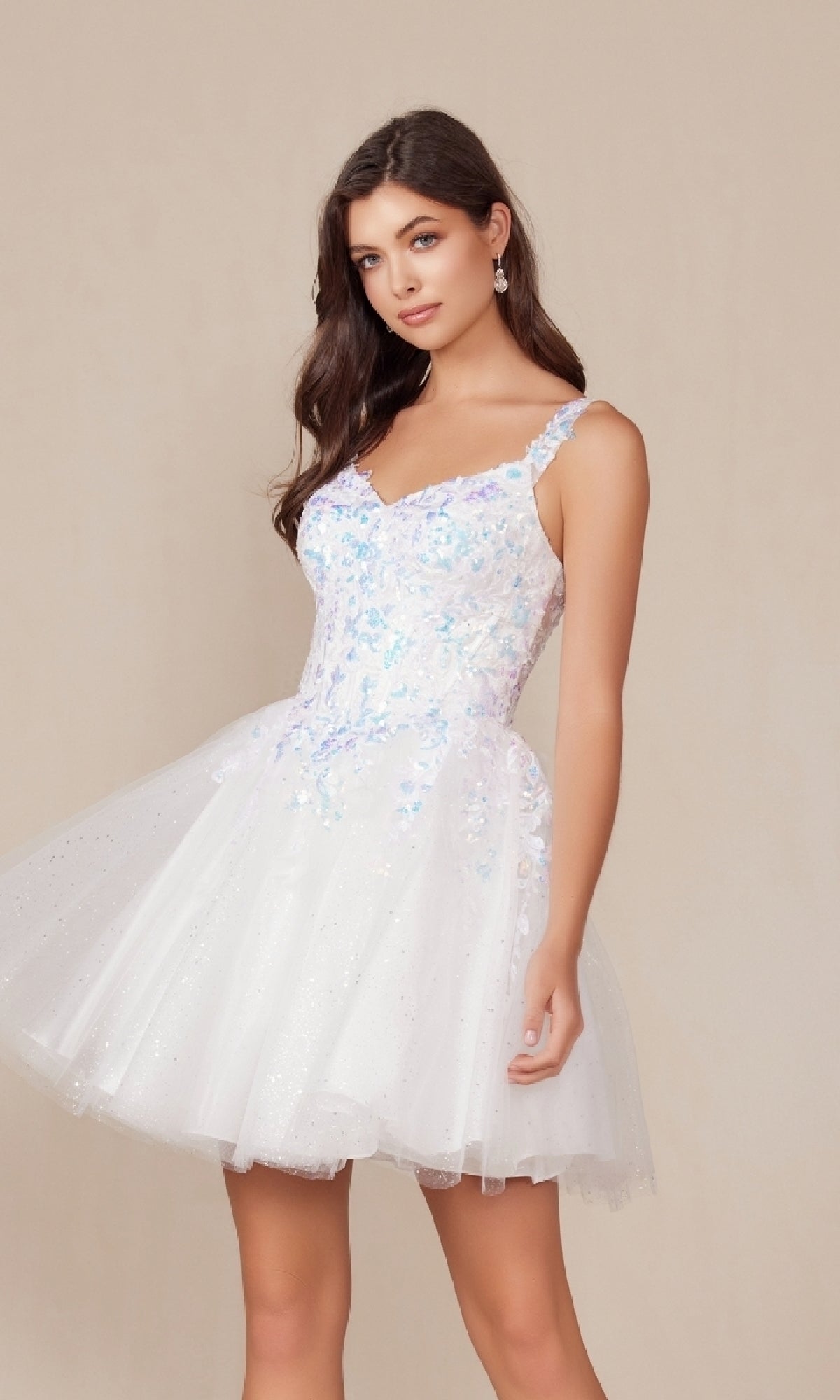 A woman wears the Short White Glitter A-Line Homecoming Dress H846W, featuring a sleeveless design and tulle skirt, while standing against a plain beige background.